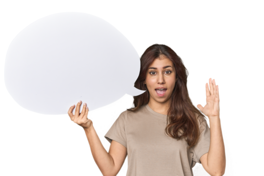 Middle Eastern woman holding comic bubble receiving a pleasant surprise, excited and raising hands.