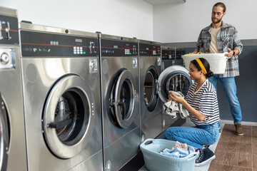 Man and woman together in commercial launderette using automatic washer and dryer
