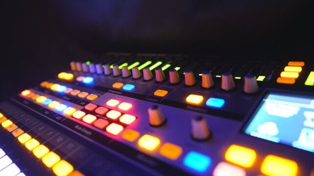 Close up of dj remote or soundboard with knobs and green color equalizer in night club. View on professional audio equipment. Slow motion