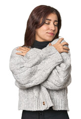 Middle Eastern woman in studio hugs, smiling carefree and happy.