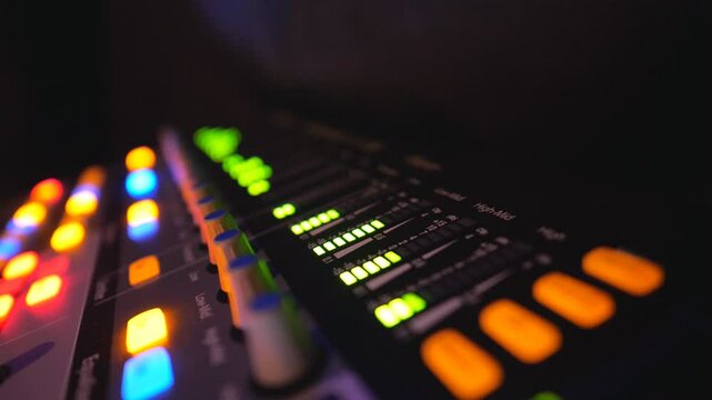 Close up of soundboard with knobs and green color equalizer in night club. View on audio waves or music control levels at professional sound equipment. Slow motion