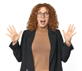 Young Caucasian redhead in business attire celebrating a victory or success, he is surprised and shocked.