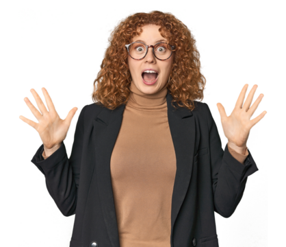 Young Caucasian redhead in business attire celebrating a victory or success, he is surprised and shocked.