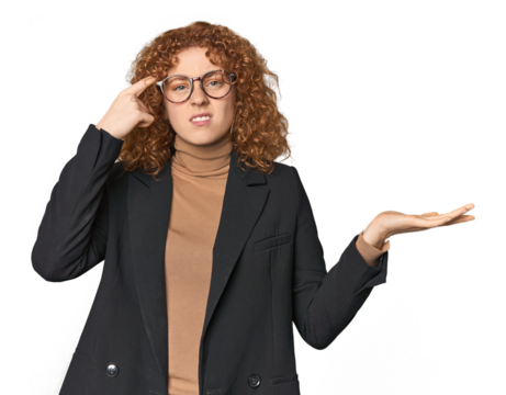 Young Caucasian redhead in business attire holding and showing a product on hand.