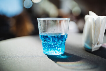 A plastic cup, brimming with a vibrant blue liquid, is placed on a table, catching the eye with its...