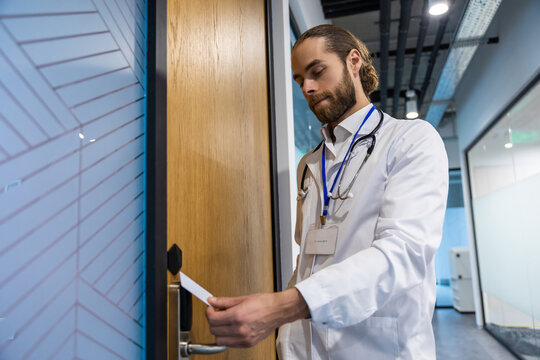 Male doctor placing key card on digital access reader in hospital to enter door