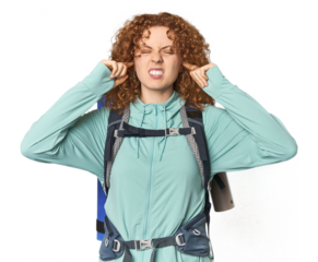 Young Caucasian redhead ready for hiking covering ears with fingers, stressed and desperate by a loudly ambient.