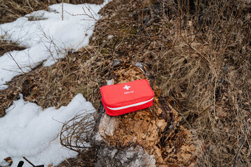 Compact Red First Aid Kit on a Snowy Forest Floor