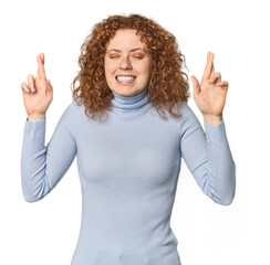 Young Caucasian redhead woman crossing fingers for having luck