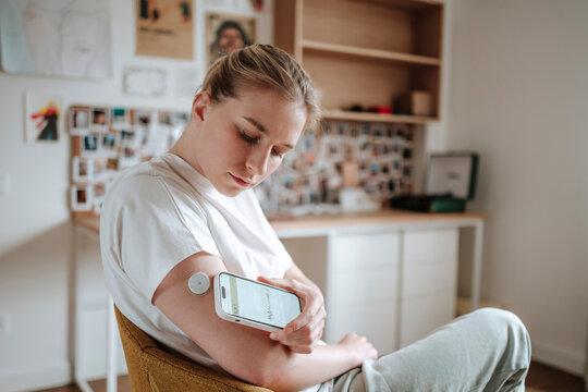 Young woman measuring glucose levels with a sensor at home
