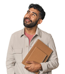 Hispanic student holding notebooks in studio dreaming of achieving goals and purposes