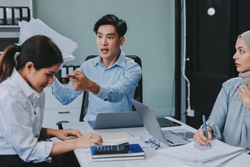 Young asian businesswoman suffering from headache while colleagues arguing and blaming her for bad...