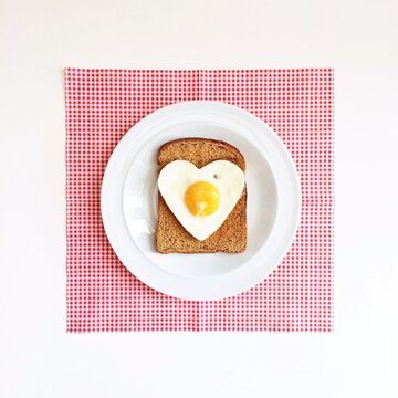 Overhead view of a Heart shaped fried egg on a slice of toasted brown bread