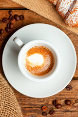Delicious italian breakfast with espresso macchiato and croissant on wooden table