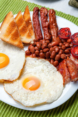 Full English breakfast with fried eggs, sausages, bacon, beans and toasts
