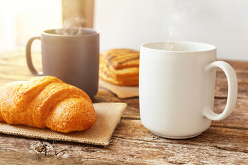 Steaming mugs and pastries creating a cozy breakfast atmosphere on a rustic wooden table