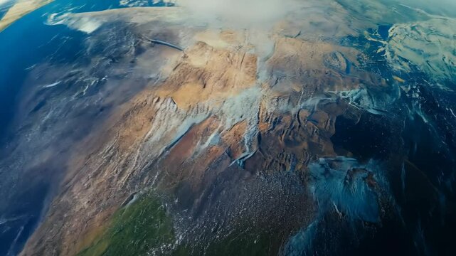 Dramatic aerial view of a vibrant mountain range, showing diverse textures, colors, and landforms under a dynamic sky