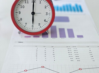 Statistics analysis with clock on financial reports highlighting data trends and performance...