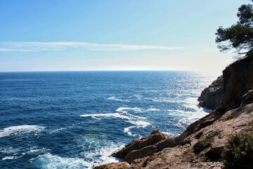 Rocky coastline with ocean waves and sky. Sea waves crashing on coastal rocks. Ocean view with...