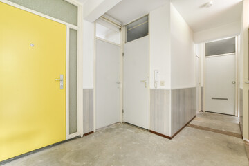 A fresh, modern hallway featuring a bright yellow door, minimalistic design, and clean lines, creating an inviting atmosphere.