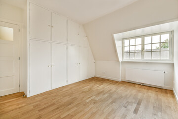 A spacious and minimalist interior featuring clean white walls, a wardrobe, and ample natural light from a large window, perfect for modern living.