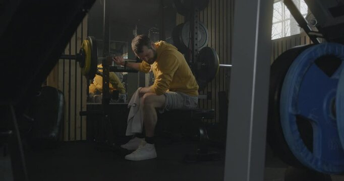 Man Resting After Workout in Home Gym, Using Towel to Wipe Sweat