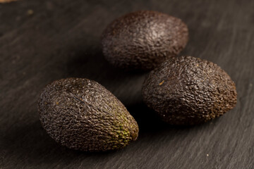 whole avocado fruits of small size on a slate, ripe avocado fruit for cooking, close up