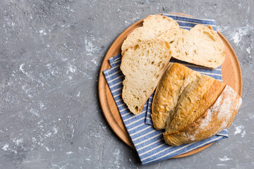 Freshly baked bread slices on cutting board against white wooden background. top view Sliced bread