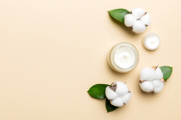 Organic cosmetic products with cotton flower and green leaves on color background. Copy space, flat lay