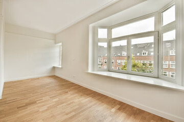 A modern interior space featuring large windows that let in natural light, showcasing a minimalist design and elegant wooden flooring, ideal for contemporary living.
