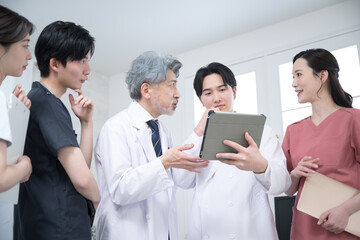 カルテや診察などの状況を確認するチーム医療の医師たち、...