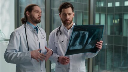 Two professional Caucasian doctors males men students interns medical people radiologist surgeon therapist discussing lungs xray image medicine talking patient treatment hospital clinic health center