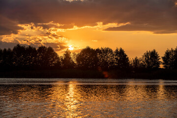 the lake with silhouetted trees, sunset on the lake shore with trees, landscape photography
