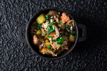 Hearty Meat and Vegetable Stew in a black pot on dark background.