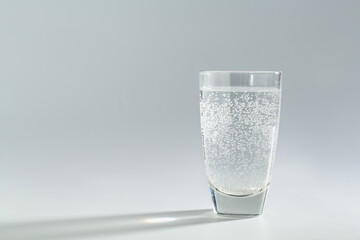 Refreshing soda water in glass on light grey background. Space for text
