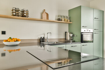 Sleek kitchen featuring green cabinetry, a polished countertop, and stylish accessories. The layout emphasizes functionality and aesthetics in a modern home setting.