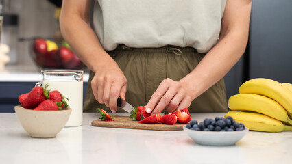 Woman cutting strawberries. Preparing fresh berries for a healthy breakfast 