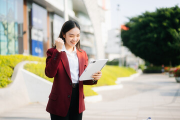 Fototapeta premium Successful businesswoman works outdoors near the office holds a tablet