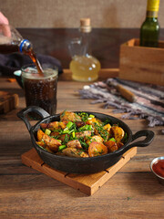 Vertical image a cooked potatoes with onions and dill in a black cast iron frying pan.