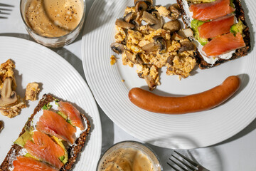 Hearty breakfast with smoked salmon, scrambled eggs, mushrooms, and sausage, celebrating rich...