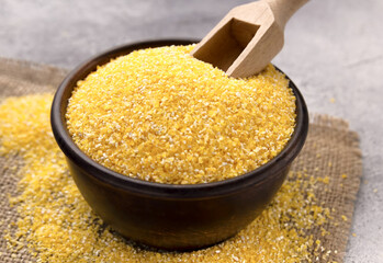 Raw cornmeal in a bowl on a gray tiled table