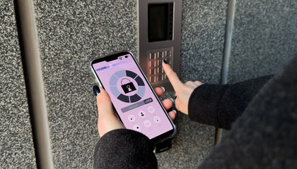 Young stylish woman getting access to the building by attaching smartphone to intercom. Concept of...