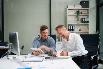Two business workers talking on the smartphone and using laptop