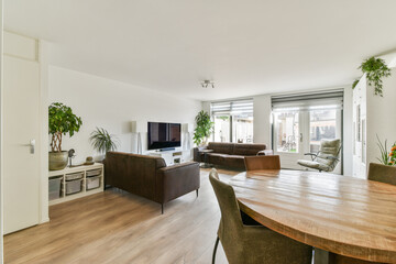 A stylish modern living room featuring minimalist furniture, large windows, and indoor plants, creating a cozy atmosphere perfect for relaxation and socializing.