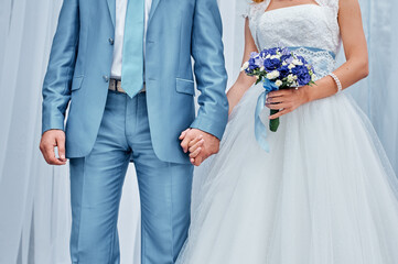 Bride and Groom Holding Hands in Elegant Wedding Attire..