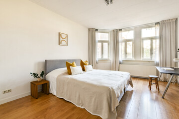 A bright and airy modern bedroom featuring a cozy bed, warm wooden flooring, and soft natural light streaming through the windows, enhancing its minimalist design.