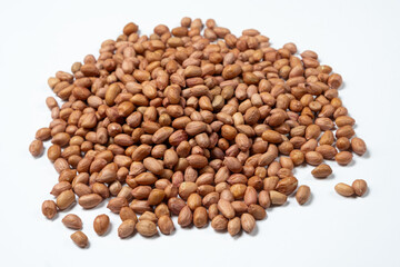 Raw peanut kernels in brown peel on white background close-up.