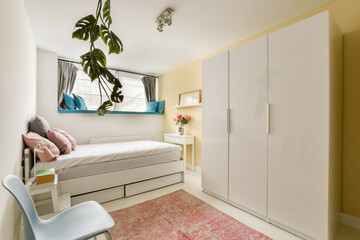 A chic and cozy bedroom featuring a minimalist design with soft colors, a stylish bed, white furniture, and a decorative rug that adds warmth to the space.