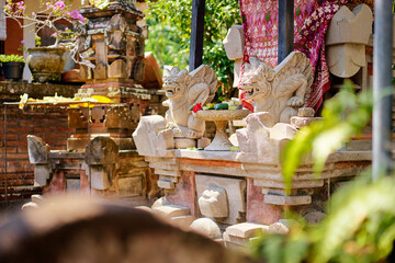 Traditional Balinese Shrine Featuring Stone Gargoyle Statues and Colorful Floral Offerings..