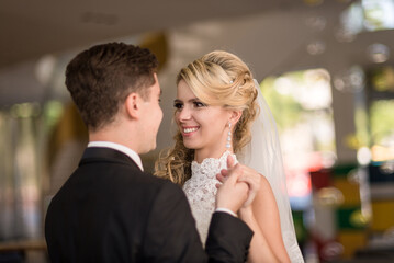 Bride and groom in a luxurious hotel lobby posing for a photographer, photo shoot in wedding dresses. Newlyweds, wedding couple in the interior, photo studio